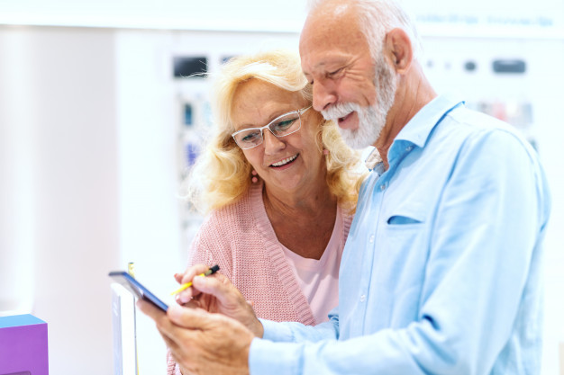 close-up-smiling-old-couple-trying-out-tablet-while-standing-tech-store_232070-1886jpg
