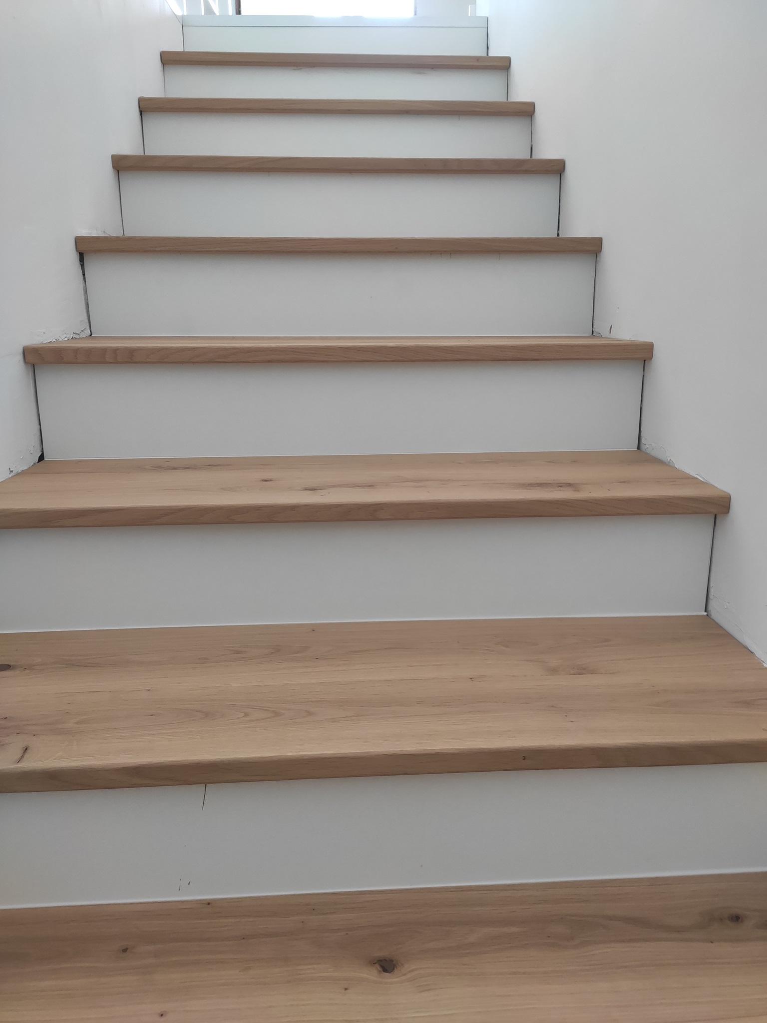 Modern, fehér elejű, svédpadlós lépcső, minimalista dizájn.