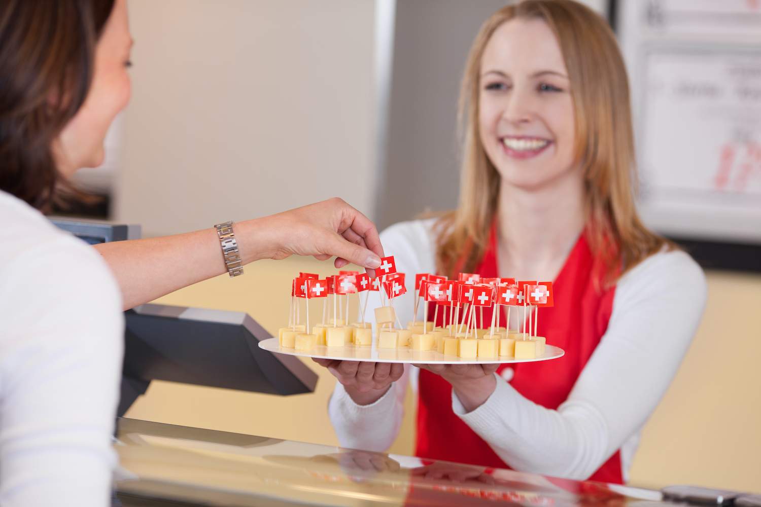 Usmiata promotérka ponúka zákazníčke promo ochutnávku nových syrov.