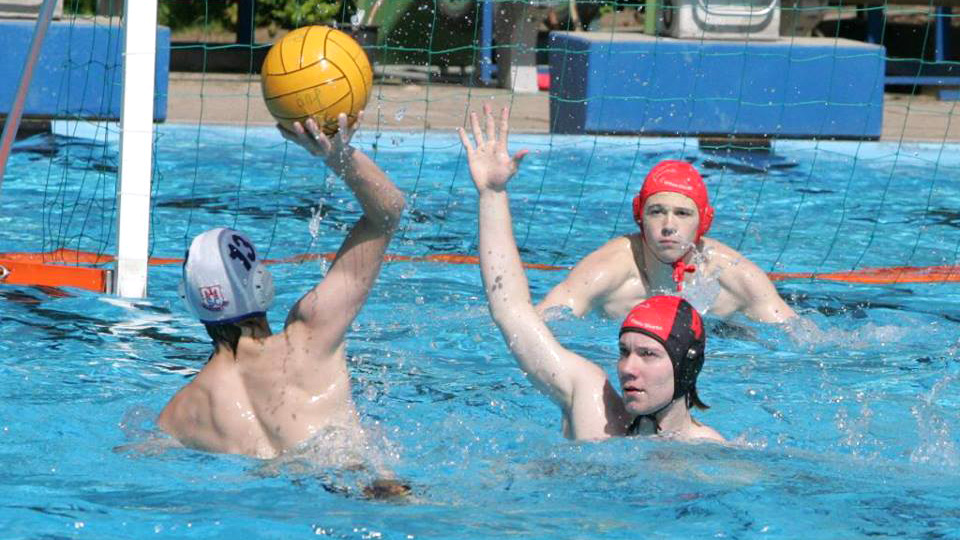 Water polo match. Water polo player with water polo cap scoring.